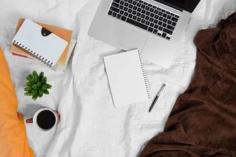Bed workspace with coffee notebook and laptop. Stock Photos