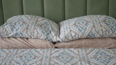 Bedding arrangement on a bed with patterned pillows Stock Footage 328966617