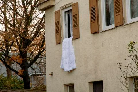 Bedding hanging out of the window of an old house Stock Photos
