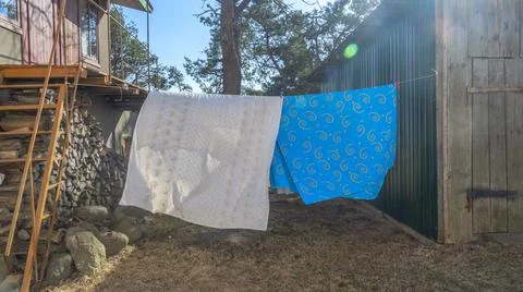 Bedding sheets drying on the clothesline outside. Lens flare. Bed linen dryin Stock Photos