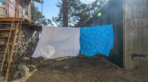 Bedding sheets drying on the clothesline outside. Lens flare. Bed linen dryin Stock Photos
