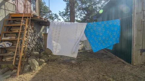 Bedding sheets drying on the clothesline outside. Lens flare. Bed linen dryin Stock Photos
