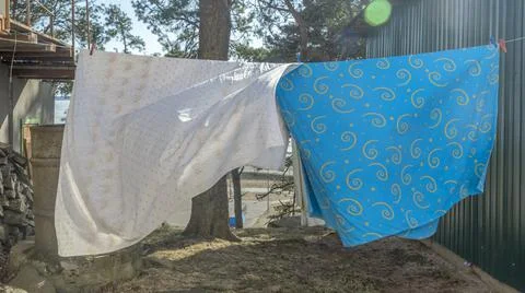 Bedding sheets drying on the clothesline outside. Lens flare. Bed linen dryin Stock Photos