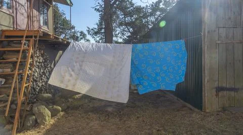 Bedding sheets drying on the clothesline outside. Lens flare. Bed linen dryin Stock Photos