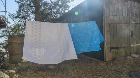 Bedding sheets drying on the clothesline outside. Lens flare. Bed linen dryin Stock Photos
