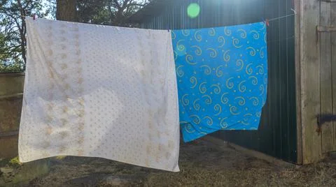 Bedding sheets drying on the clothesline outside. Lens flare. Bed linen dryin Stock Photos