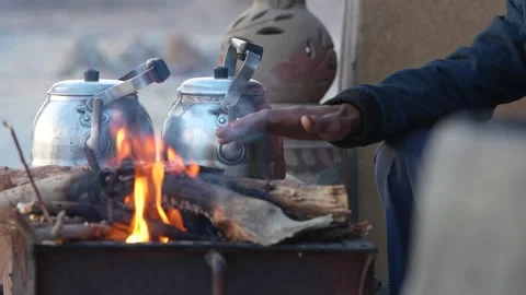 Bedouin man warming his hands over campfire making tea Stock Footage 333565663