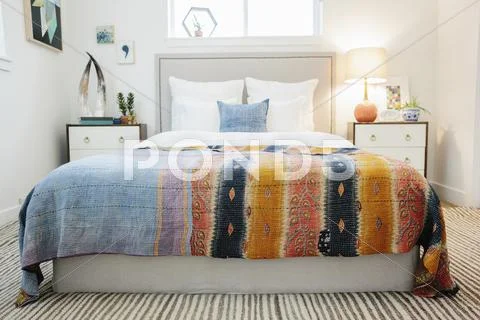 A bedroom and a vivid striped patterned bedspread. Stock Photos