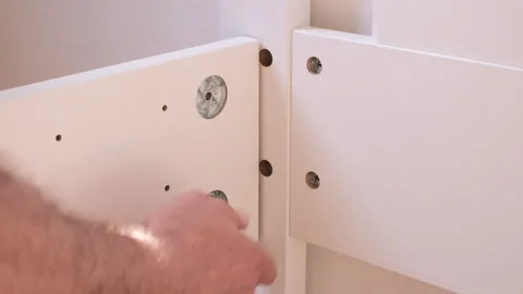 Bedroom assembling a New wooden bed. Man tighten by hex key the furniture b.. Stock Footage 242437588