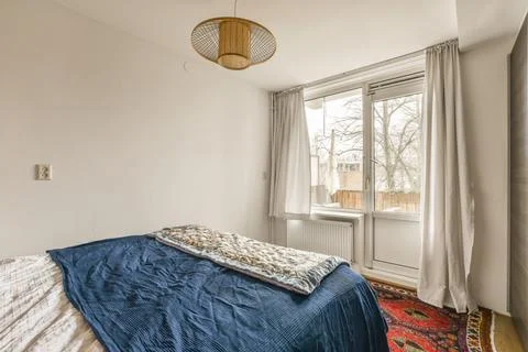 A bedroom with a bed and a window Stock Photos