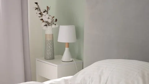 Bedroom decor: bed, bedside table, plant and lamp. Create a cozy atmosphere in Stock Footage 275820900