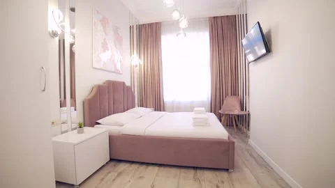 Bedroom interior, modern style, large bed, light colors, white, pink, beige Stock Footage 152509692
