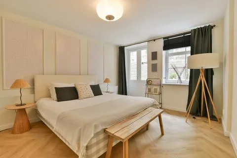 A bedroom with a large bed and a window Stock Photos