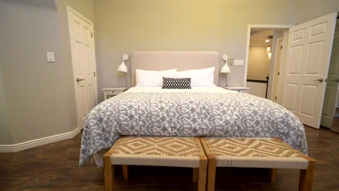 Bedroom with patterned bedspread and woven benches Stock Footage 345693993