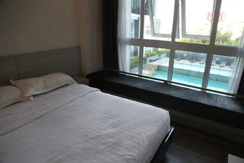 The bedroom on the third floor has an open window, with white sheets and bl.. Stock Photos