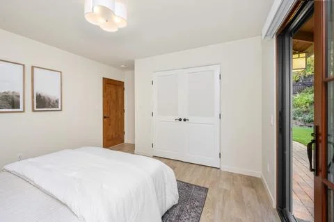A bedroom with two pictures hung above the bed and sliding glass doors to an out Stock Photos