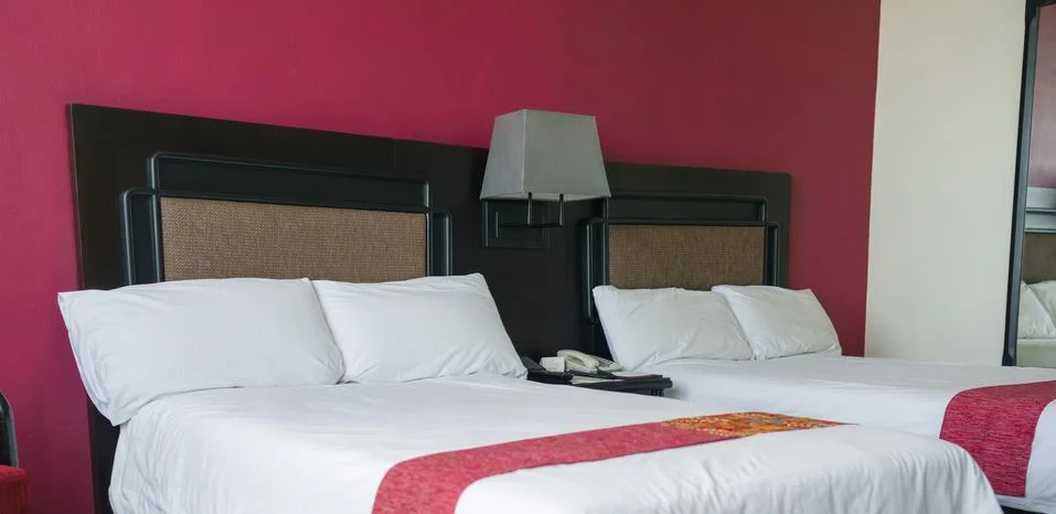 Beds with pillows and table between in luxury hotel room Stock Photos