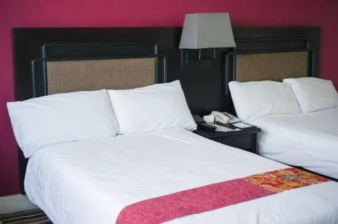 Beds with pillows and table between in luxury hotel room Stock Photos