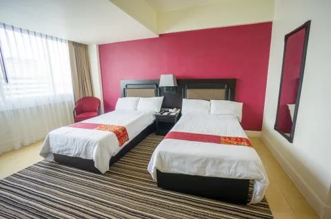 Beds with pillows and table between in luxury hotel room Stock Photos