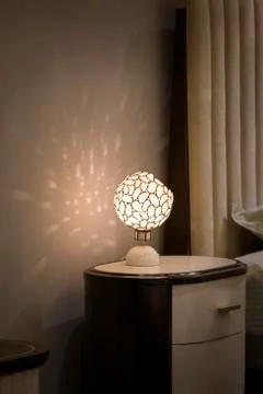Bedside night lamp of a round form with a beautiful pattern. The lamp creates Stock Photos