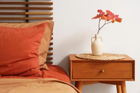 Bedside table and autumn decor in interior of stylish bedroom, closeup Stock Photos