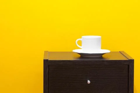 Bedside table and cup against a yellow wall in the apartment Foto stock