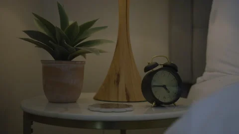 Bedside Table With Clock Plant And Lamp Stock Footage 208784883
