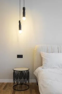 Bedside table with hanging lamp in the bedroom Stock Photos