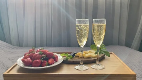 Bedside table with two glasses of champagne and a sweet dessert Stock Footage 129611527