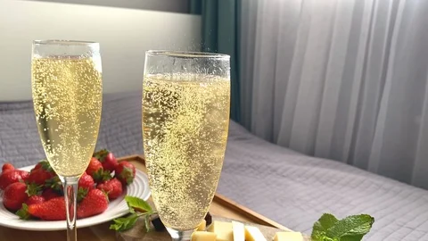 Bedside table with two glasses of champagne and a sweet dessert Stock Footage 129611528