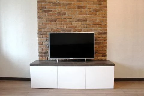 Bedside table under the TV against a brick wall Stock Photos