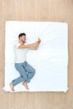 Bedtime. Guy lying on bed top view taking selfie on smartphone cheerful Stock Photos