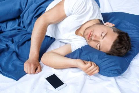 Bedtime. Guy sleeping peaceful on bed top view Stock Photos