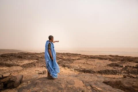 Beduin pointing to remaining walls of ancient neolithic village in the Sahara Stock Photos