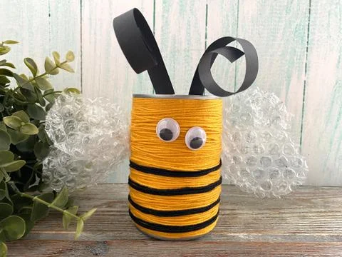 Bee made of wool yarn and cans, on a wooden background, children's creativity, Stock Photos