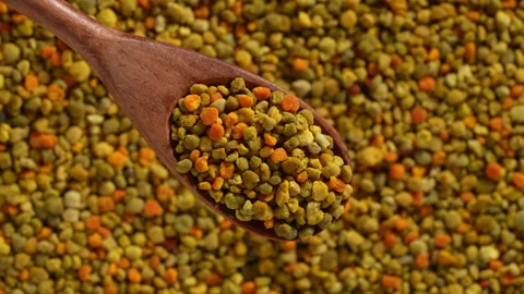 Bee pollen granules texture background with wooden spoon, close up, rotates Stock Footage 344765108