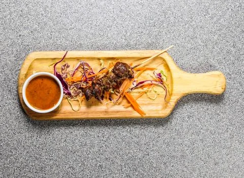 Beef bbq satay with chilli sauce served on wooden bard isolated on grey bac.. Stock Photos