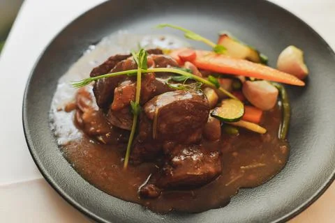 Beef Bourguignon with vegetables in a black plate Fotos Stock
