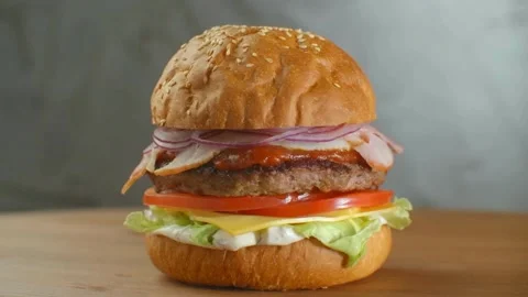 Beef Burger rotating on the table on a black background. plate on grey Vídeo Stock 336579325