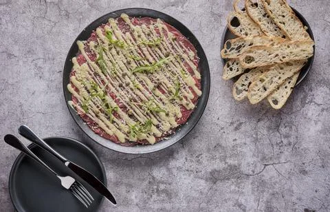 Beef Carpaccio cold appetizer with parmesan, capers and arugula on black plate Stock Photos
