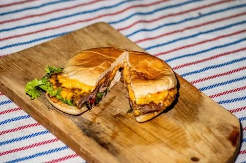 A beef cheese burger that is split with a knife filled with meat, tomato sa.. Stock Photos