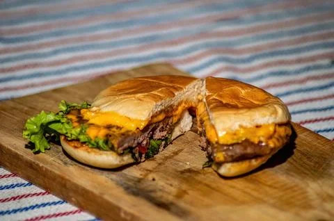 A beef cheese burger that is split with a knife filled with meat, tomato sa.. Stock Photos