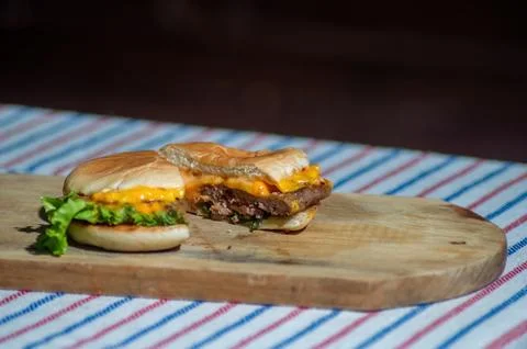 A beef cheese burger that is split with a knife filled with meat, tomato sa.. Stock Photos