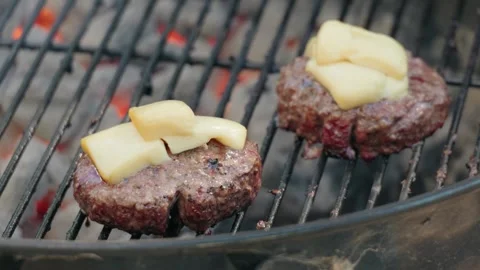 Beef cheeseburger patties with melted cheese sizzle on outdoor grill Stock-Footage 342511940
