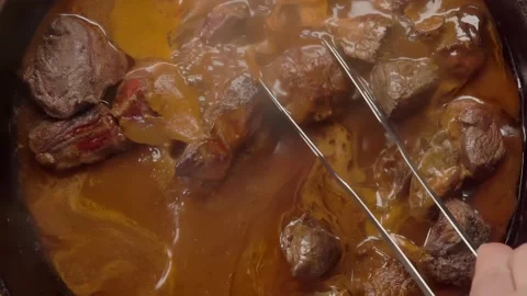 Beef chunks simmering in sauce in wok for hearty vegetable stew Stock Footage 309448676