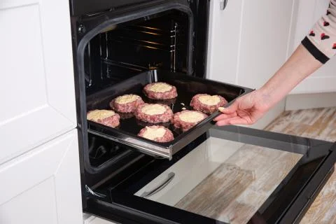 Beef cutlets on the baking tray put into oven Stock Photos