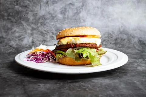 Beef egg and cheese burger include tomato, onion and lettuce leaves served .. Stock Photos