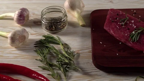 Beef fillet on a desk with pepper, rosemary and garlic. Stock Footage