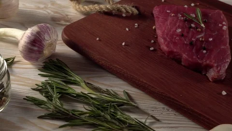 Beef fillet on a desk with pepper, rosemary axe and garlic. Stock Footage