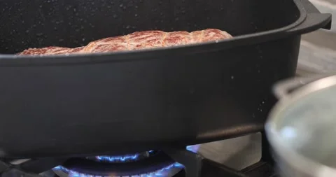 Beef is fried in cauldron on gas stove and splashed with oil Stock Footage 168663979